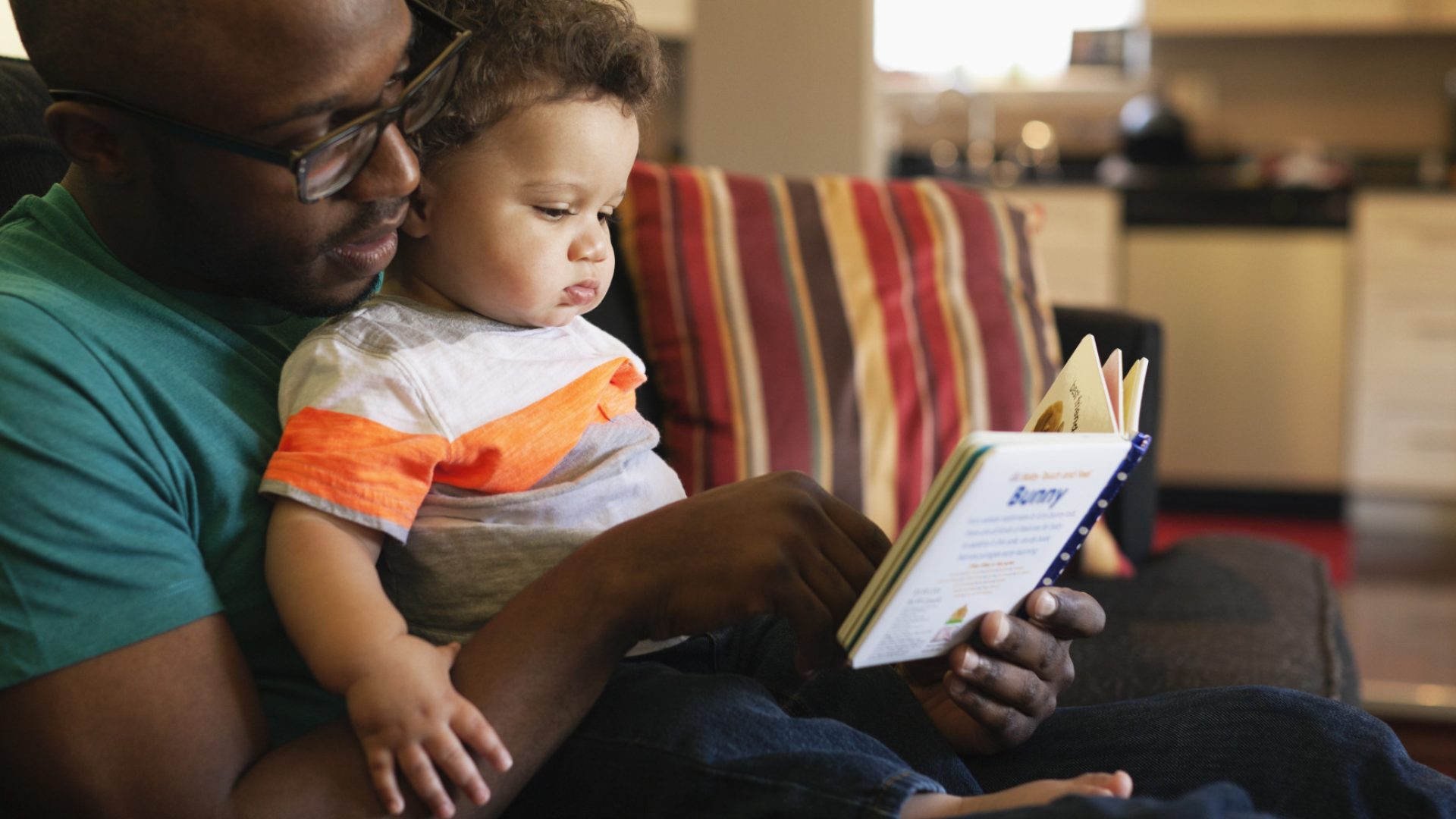 Father reading to baby on sofa